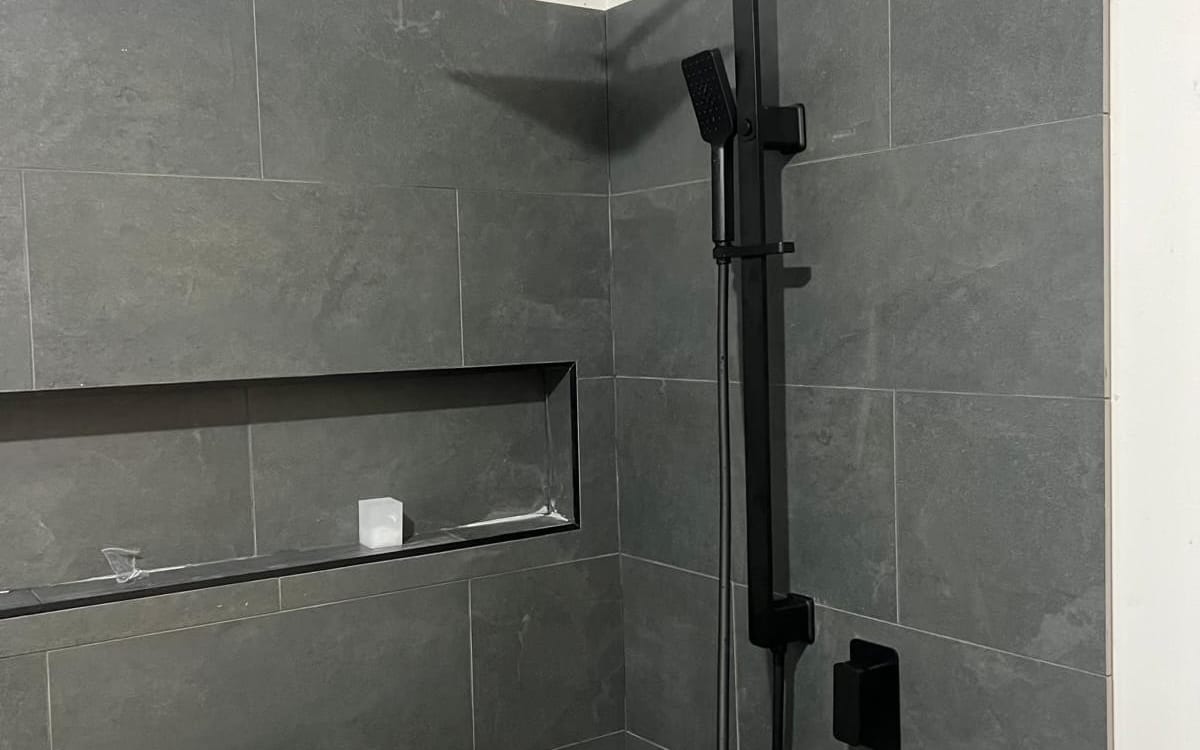 Renovated shower with black fittings and a tiled niche