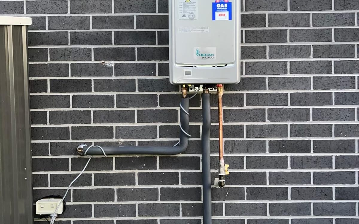 Continuous flow hot water system installed on a brick wall