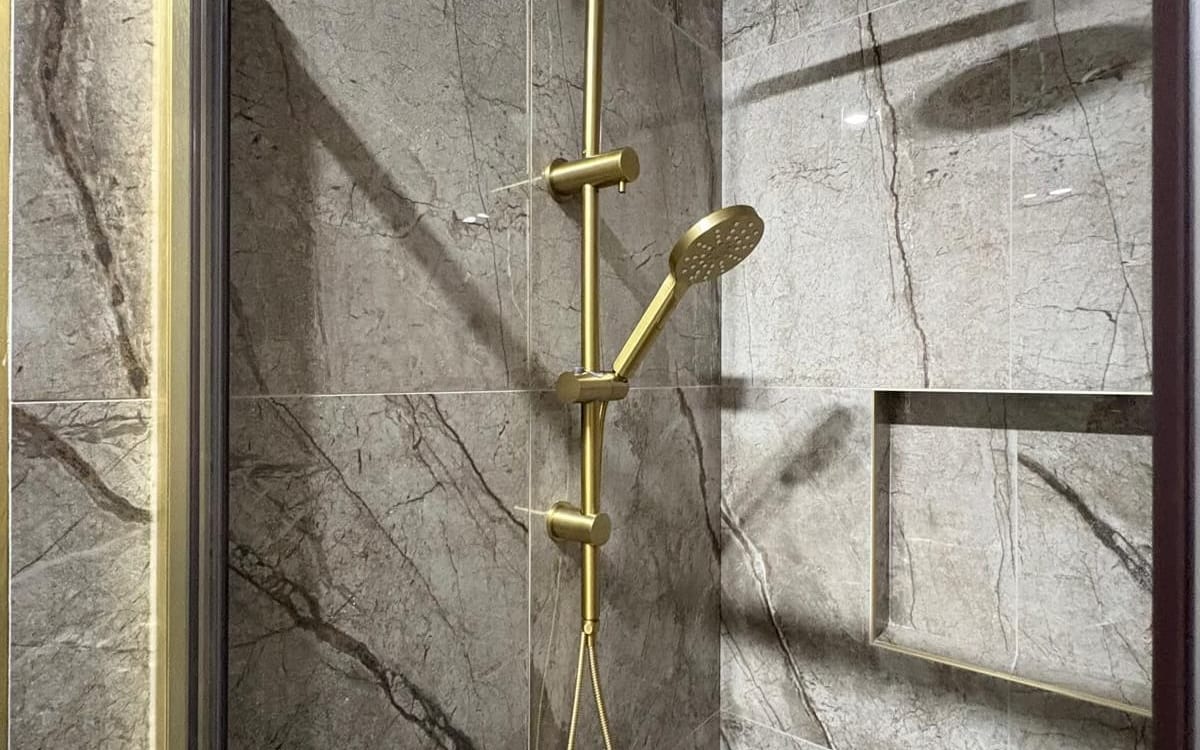 Brass shower mixer and rail in a tiled shower