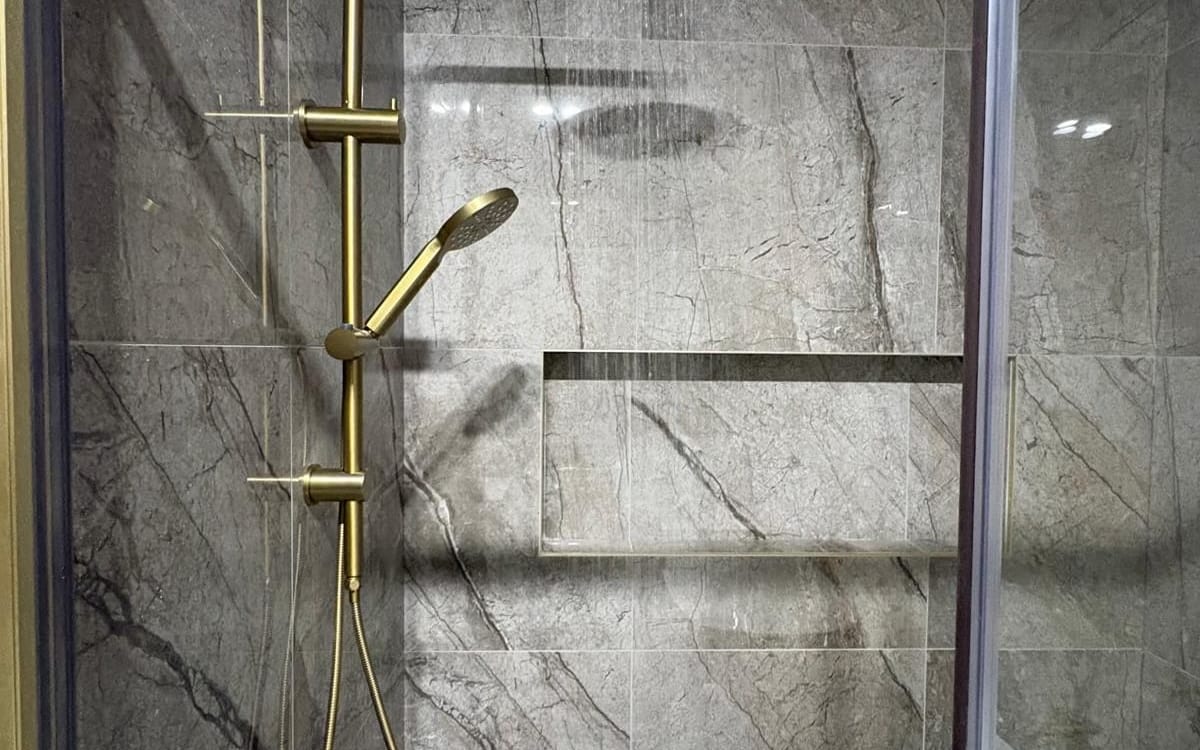 Rainfall shower running in a tiled bathroom